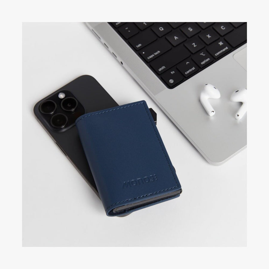 Oxford Blue / Black | Slim Wallet Pro in Oxford Blue / Black placed on a desk alongside wireless earbuds, laptop, and a smartphone, highlighting its sleek and modern design in a lifestyle setting.